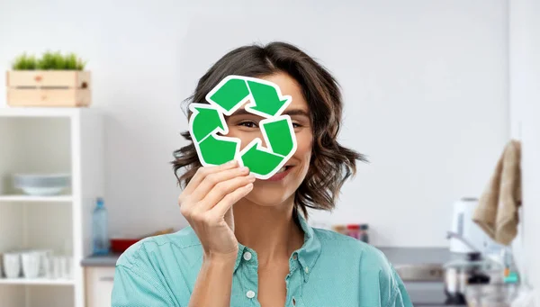 Mulher sorrindo olhando através do sinal de reciclagem verde — Fotografia de Stock