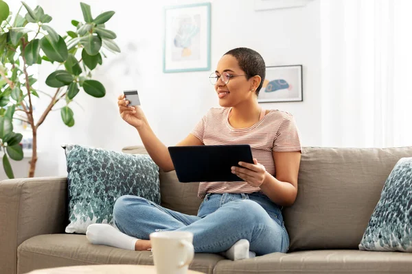 Mulher feliz com tablet pc e cartão de crédito em casa — Fotografia de Stock