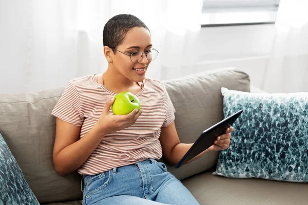 African woman with tablet pc and apple at home — Stock Photo, Image