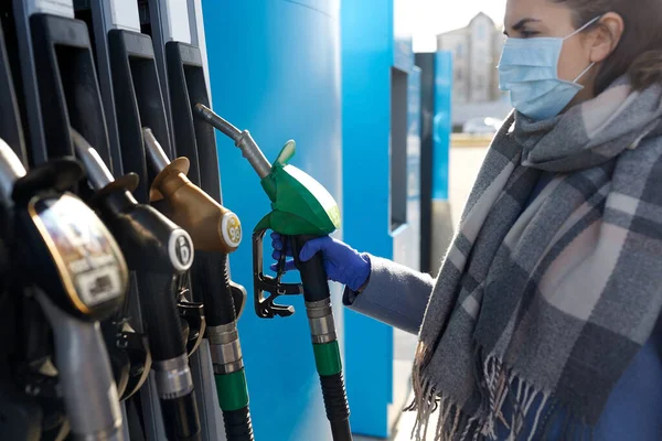 Junge Frau mit Schutzmaske an Tankstelle — Stockfoto