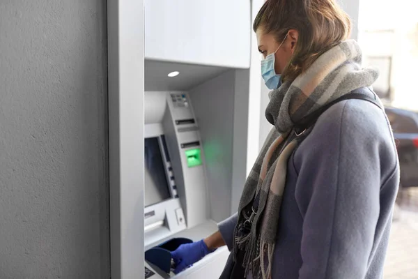 마스크와 장갑 치료 코드를 쓰고 있는 여성 at atm — 스톡 사진