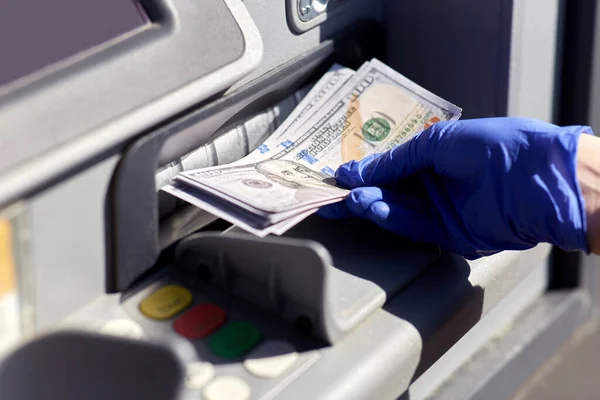 Рука в медичній рукавичці з грошима в машині атм — стокове фото