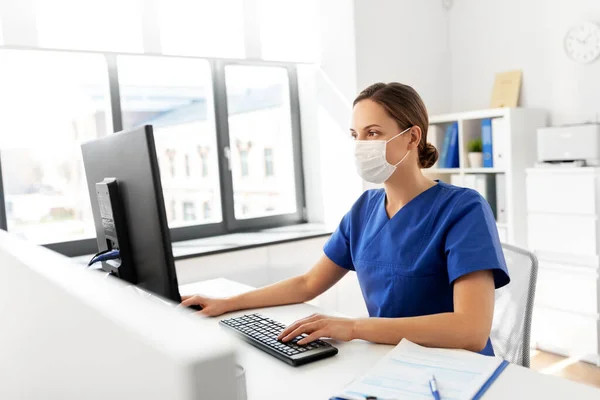 Médico o enfermero con máscara y computadora en el hospital Imágenes de stock libres de derechos