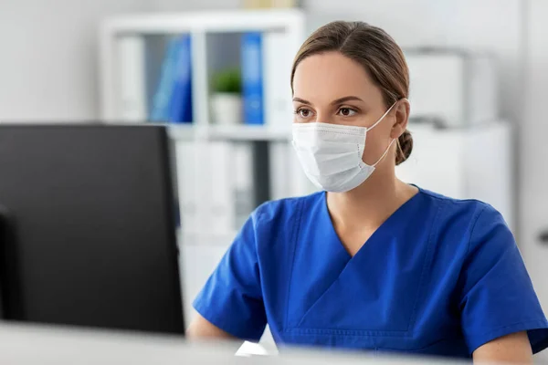 Medico o infermiere in maschera con computer in ospedale — Foto Stock