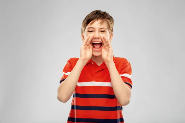 Pojke i röd polo t-shirt skriker eller ringer — Stockfoto