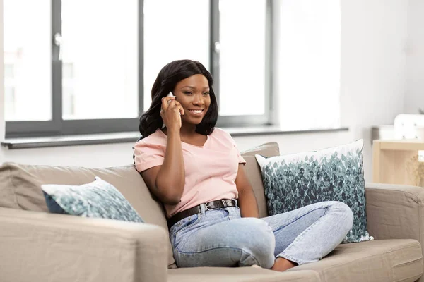 Afrikalı bir kadın evde akıllı telefondan arıyor. — Stok fotoğraf