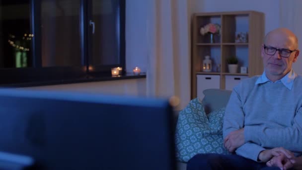 Couple aîné regarder la télévision à la maison le soir — Video