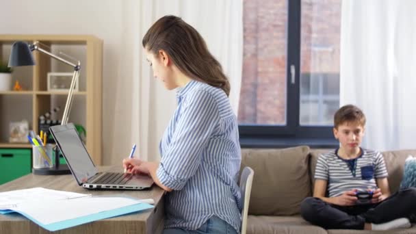 Madre trabajando en casa e hijo jugando videojuego — Vídeos de Stock