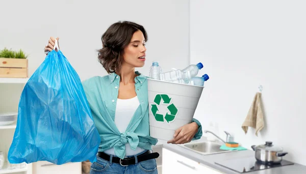 Mujer sonriente clasificación de residuos de plástico y bolsa de basura — Foto de Stock