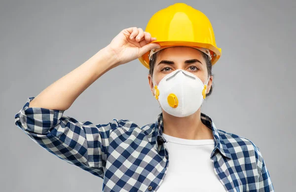 Kvinnlig arbetare eller byggare i hjälm och respirator — Stockfoto