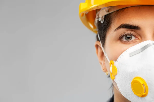 Kvinnlig arbetare eller byggare i hjälm och respirator — Stockfoto