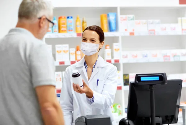 Apotheker mit Maske und Seniorkunde in der Apotheke — Stockfoto