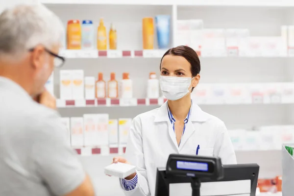 Apotheker in Maske zeigt Mann in Apotheke Medikament — Stockfoto