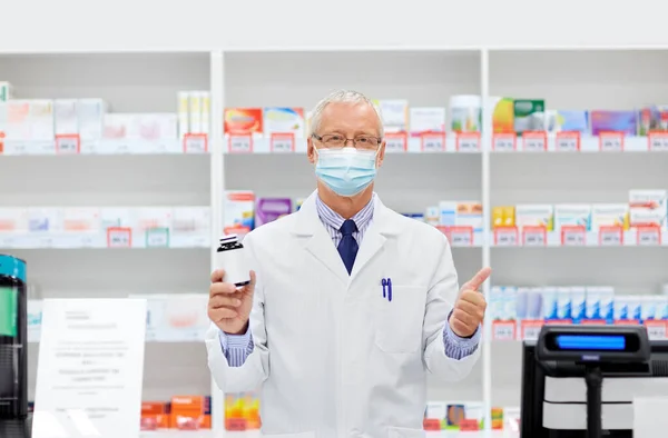 Apothicaire senior masqué avec médicament à la pharmacie — Photo