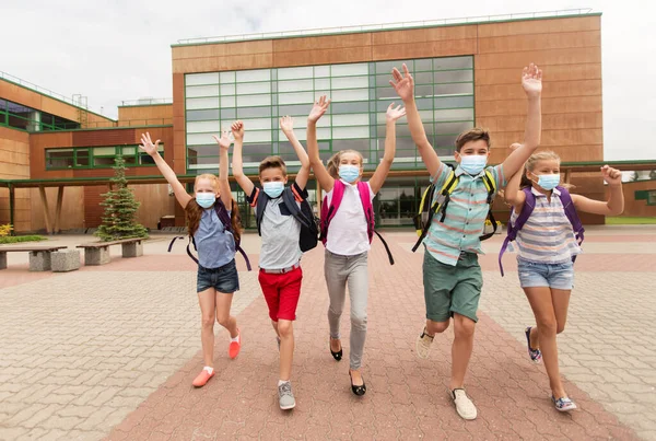 Grupa szczęśliwych uczniów w maskach opuszczających szkołę — Zdjęcie stockowe