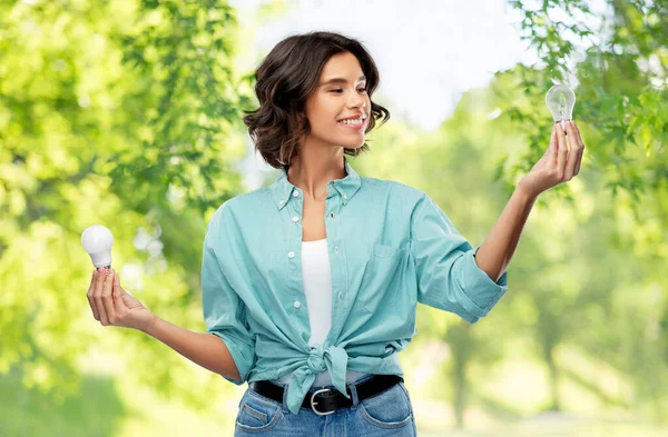 Smiling woman comparing different light bulbs — Stock Photo, Image