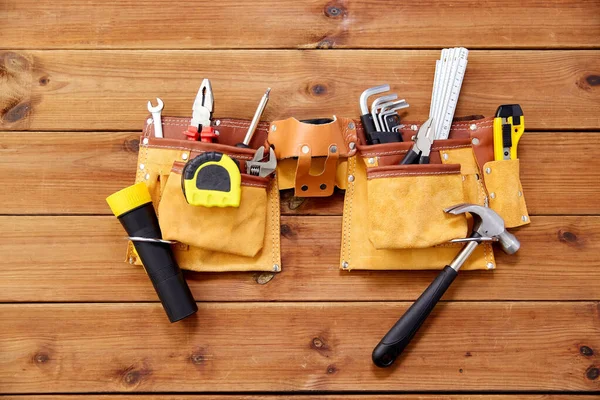 Different work tools in belt on wooden boards — Stock Photo, Image