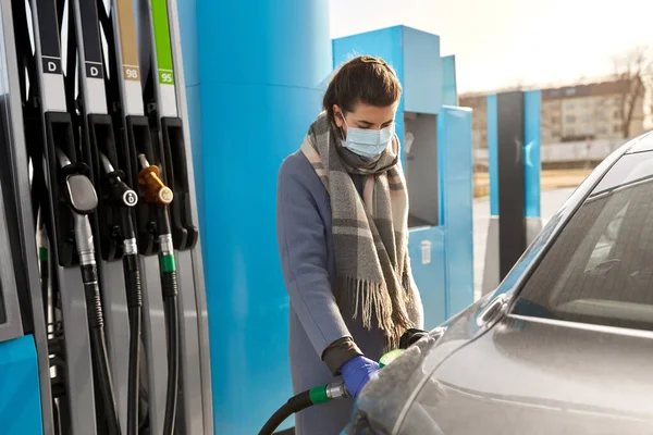 Vrouw in masker vullen auto bij tankstation — Stockfoto