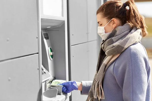 Mujer en máscara médica y guante con dinero en el cajero automático — Foto de Stock