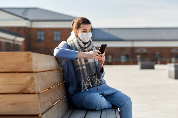 Mujer en máscara facial con smartphone en la ciudad — Foto de Stock