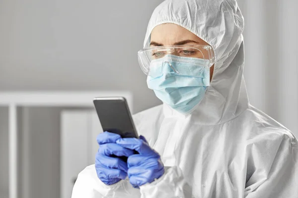Médico en ropa protectora con smartphone —  Fotos de Stock