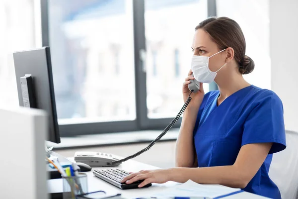 Arts met computer bellen op telefoon in het ziekenhuis — Stockfoto