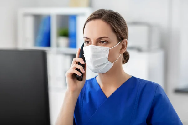 Doctor con computadora llamando por teléfono en el hospital —  Fotos de Stock