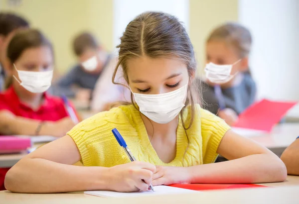 Skupina studentů v maskách písemný test ve škole — Stock fotografie