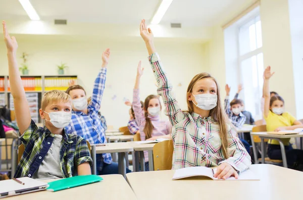 Gruppo di studenti in maschera alzando le mani a scuola — Foto Stock