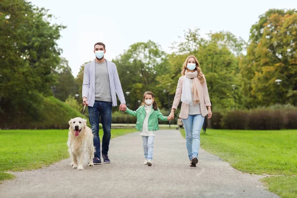 Familie in maskers met labrador hond in park — Stockfoto