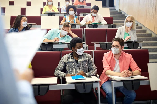 Skupina studentů v maskách v přednáškovém sále — Stock fotografie
