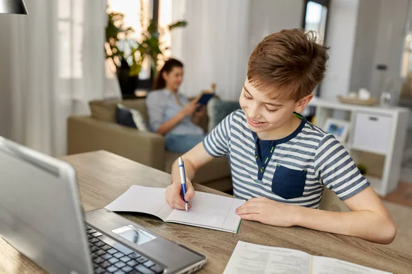 Studente ragazzo con libro scrittura per notebook a casa — Foto Stock
