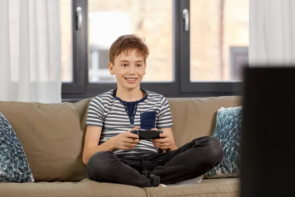 Chico con gamepad jugando videojuego en casa — Foto de Stock