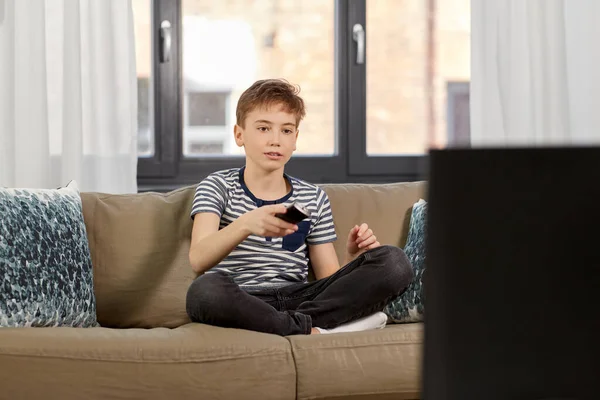 Menino com controle remoto assistindo tv em casa — Fotografia de Stock