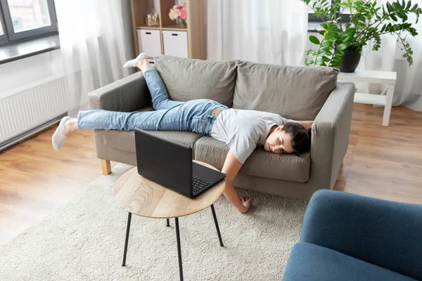 Нудна жінка з ноутбуком лежить на дивані вдома — стокове фото