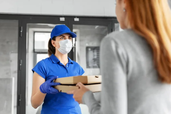 Entrega menina em máscara dando caixas de pizza para mulher — Fotografia de Stock