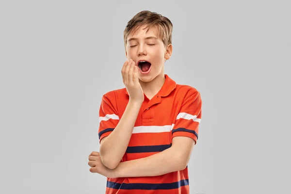 Portrait of tired yawning boy in red polo t-shirt — Stock Photo, Image