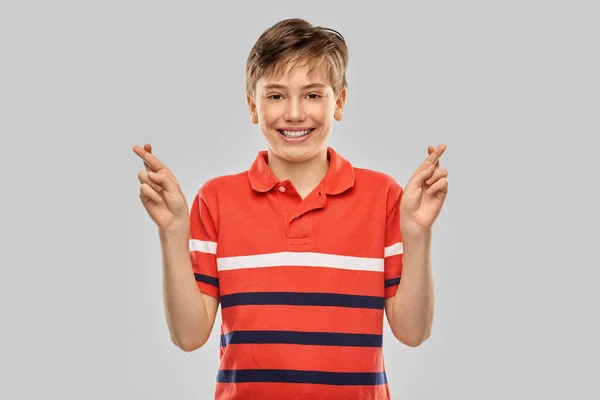 Glimlachende jongen in t-shirt houdt vingers gekruist — Stockfoto