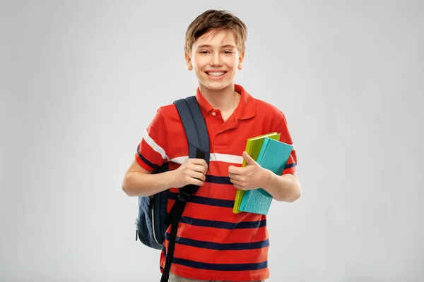 Sırt çantası ve kitapları olan gülümseyen öğrenci. — Stok fotoğraf