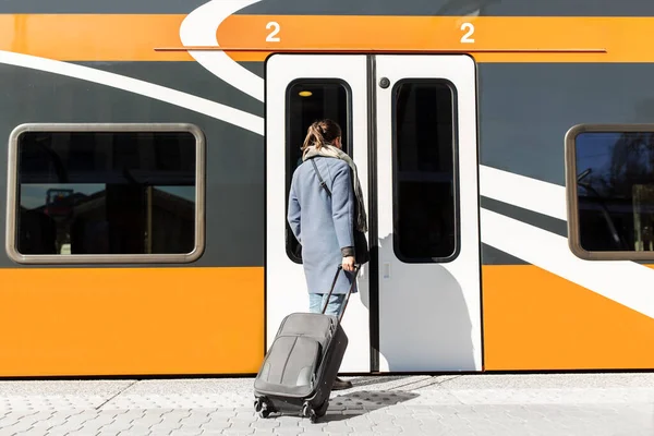 Vrouw met koffer op station Stockafbeelding