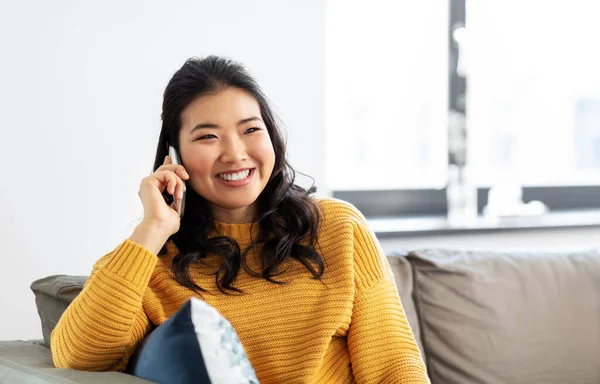 Glimlachende aziatische vrouw bellen op smartphone thuis — Stockfoto