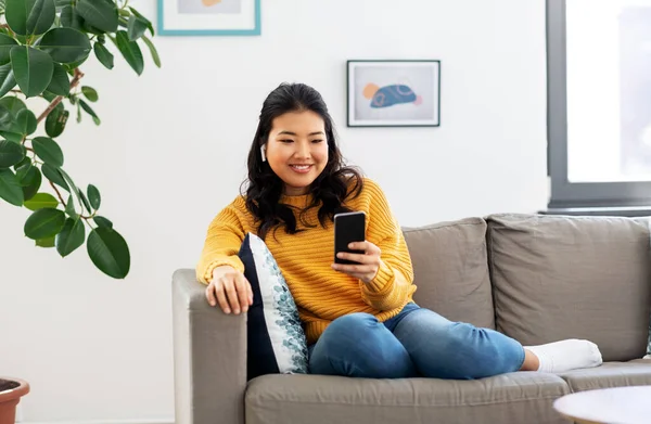 Mulher asiática com fones de ouvido e smartphone em casa — Fotografia de Stock