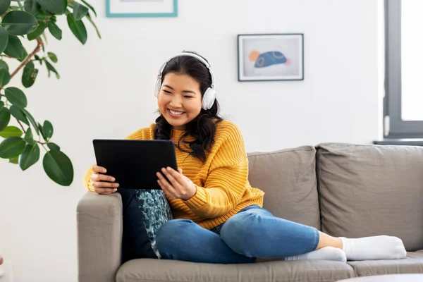 Mulher asiática com fones de ouvido e tablet pc em casa — Fotografia de Stock