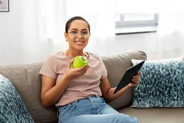African woman with tablet pc and apple at home — Stock Photo, Image