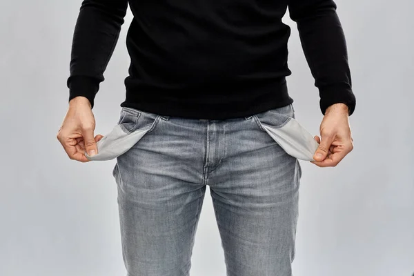 Close up of man showing empty pockets over grey — Stock Photo, Image