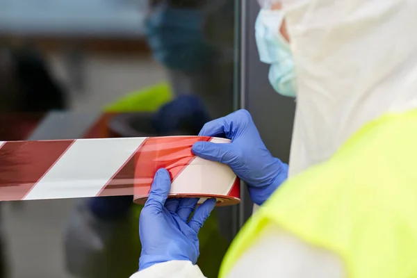 Trabajador de la salud sellando la puerta con cinta de precaución —  Fotos de Stock