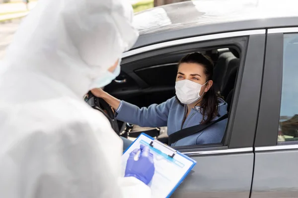Trabajador sanitario con portapapeles y mujer en coche — Foto de Stock
