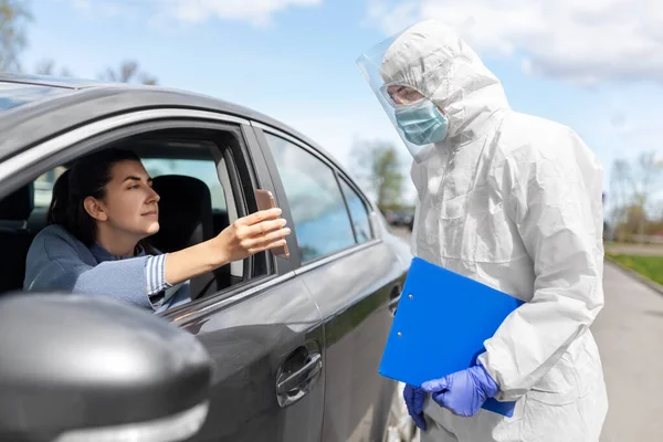 Woman in car showing phohe to healthcare worker Stock Picture