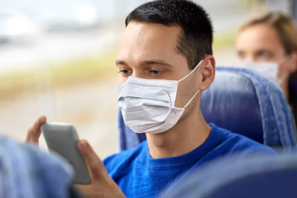 Человек в маске с помощью смартфона в автобусе — стоковое фото
