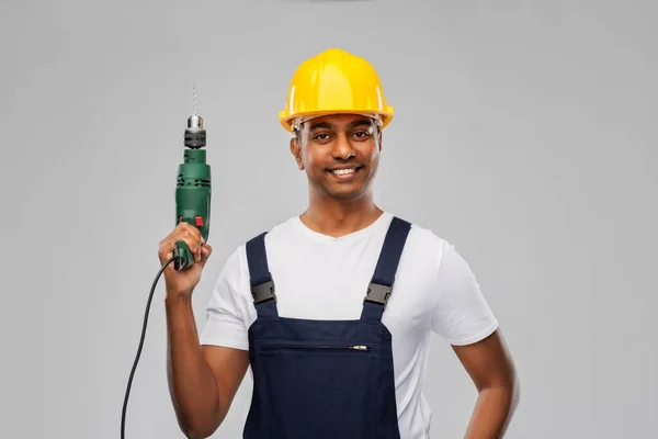 Счастливый индийский строитель в шлеме с электрической дрелью — стоковое фото